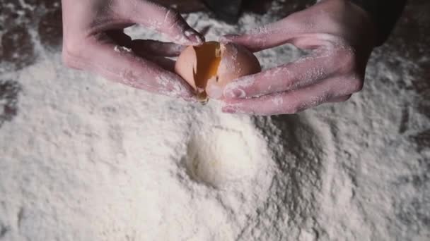 Een close-upshot van een vrouwelijke chef-kok die eieren kraakt in meel. Langzame beweging van vallende eieren in meelbouillon. Beeldmateriaal eten. Eieren vallen in bloem, slow motion. Yolk Falls. Voedsel Blog, Meel Producten — Stockvideo