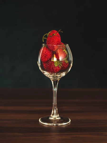 Fresh strawberries in wine glass on table. Ripe strawberry closeup. Sweet summer harvest. Juicy dessert. Healthy food. Red berries in glass vase on unfocused background. Freshness concept.
