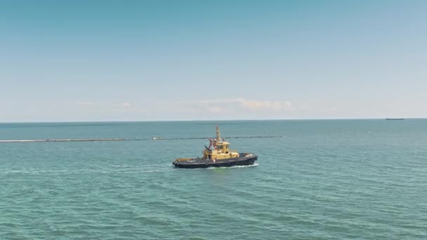 Flygdrönare video av gul bogserbåt går till ett stort lastfartyg för att transportera till bryggan. Lastfartyg pråm och bogserbåt segla för att möta varandra i hamnen. Flygvy. — Stockvideo