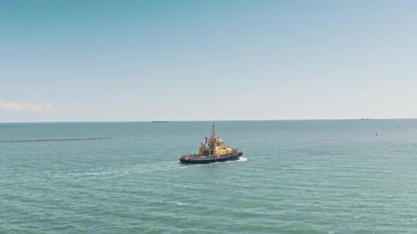 Aerial drone video of yellow tugboat goes to a large cargo ship to transport to the dock. Cargo ship barge and tugboat sail to meet each other in the seaport of the port. Aerial View. — 图库视频影像