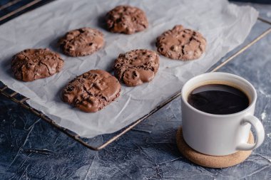 Siyah taştan arka planda beyaz kahve ve çikolatalı kurabiye. Güzel, anlaşıldı. Çikolatalı ev yapımı kurabiyeler..