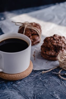 Siyah taştan arka planda beyaz kahve ve çikolatalı kurabiye. Güzel, anlaşıldı. Çikolatalı ev yapımı kurabiyeler..