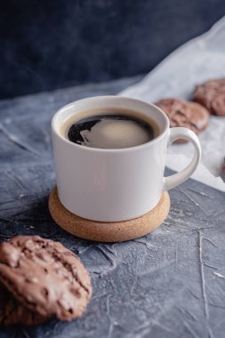 Siyah taştan arka planda beyaz kahve ve çikolatalı kurabiye. Güzel, anlaşıldı. Çikolatalı ev yapımı kurabiyeler..
