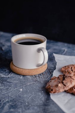 Siyah taştan arka planda beyaz kahve ve çikolatalı kurabiye. Güzel, anlaşıldı. Çikolatalı ev yapımı kurabiyeler..