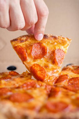 Erkek el, pepperoni pizzasının ilk dilimini teslimat kutusundan çıkarır. Fast food konsepti.