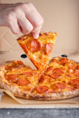 Erkek el, pepperoni pizzasının ilk dilimini teslimat kutusundan çıkarır. Fast food konsepti.