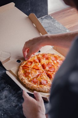 Erkek el, pepperoni pizzasının ilk dilimini teslimat kutusundan çıkarır. Fast food konsepti.