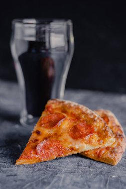 Siyah tahtada pizza dilimleri, geleneksel İtalyan pizzası, bir bardak kola..