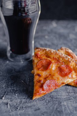 Siyah tahtada pizza dilimleri, geleneksel İtalyan pizzası, bir bardak kola..