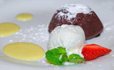 Dondurma ve çilek beyaz bir plaka üzerinde bir kepçe ile sıcak çikolatalı fondan.