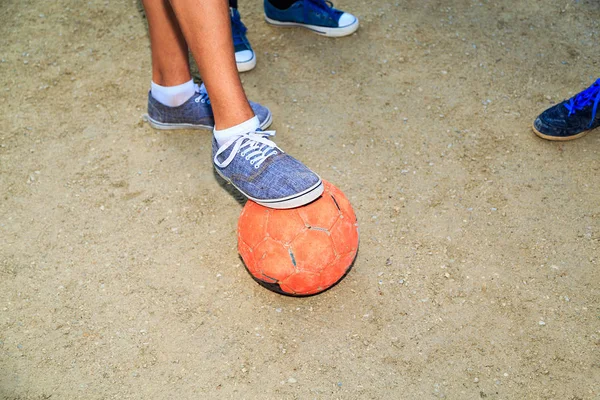 Street football. Boys feet with the ball in the sand