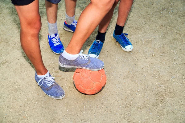 Street football. Boys feet with the ball in the sand