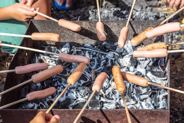 Dzieci nastolatków smażyć kiełbasy na grillu — Zdjęcie stockowe