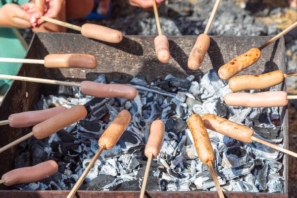 Children teenagers fry sausages on the grill — Stock Photo, Image