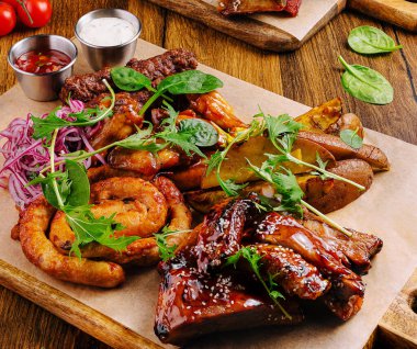 Canlı bir tabakta, taze yeşilliklerle süslenmiş ve lezzetli soslarla eşleştirilmiş tavuk kanatları ve kaburgalar da dahil olmak üzere çeşitli ızgara etler yer alıyor..