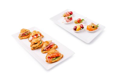 Çeşitli aperatiflerde sebze ve etlerle dolu hassas kruvasanlar ve renkli meyve şişleri, toplanma ve partiler için cazip bir yayılma yaratıyor..
