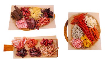 Çeşitli pişmiş etler ve kurutulmuş malzemeler ahşap tahtalarda düzenlenir. Canlı renkler ve dokular toplanma ya da ziyafet için uygun bir sunum oluşturuyor..