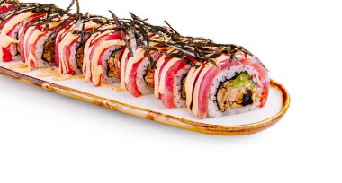Renkli bir suşi rulosu zarif beyaz bir tabakta dikkatlice sunuluyor..