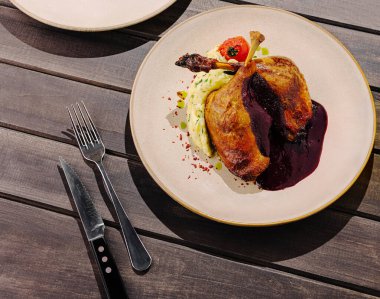 Koyu ahşap bir masanın üzerindeki tabaklara üç gurme yemek güzelce yerleştirilmiştir. Biri böğürtlen soslu ördek, diğeri balık ve sonuncusu da kenarlı lezzetli et yemeği..