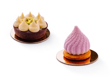 Altın dairesel temellerde iki enfes tatlı sergilenir. Biri fındık kremalı zengin bir çikolatalı tart, diğeri de tereyağlı kurabiyenin tepesinde narin mor bir krema..