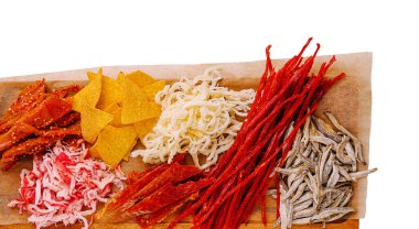 Ahşap bir tahtada günün herhangi bir saatinde toplanma sırasında paylaşmak için mükemmel kurutulmuş balık, doğranmış et ve çıtır cips de dahil olmak üzere bir dizi renkli geleneksel abur cubur yer alır..