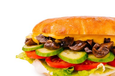 İçinde sotelenmiş mantarlar, kıtır marul, taze domates ve salatalık dilimleri olan doyurucu bir sandviç, hepsi yumuşak bir çöreğin içinde.