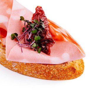 Lezzetli bir aperatif, taze mikro yeşilliklerle süslenmiş, taze et ve kurutulmuş domates katmanları sergiliyor..