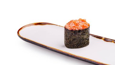 Basit bir dikdörtgen tabakta bir parça somon balığı sunulur. Suşi deniz yosununa sarılmış ve taze doğranmış somonla kaplanmış. Canlı rengini ve dokusunu vurguluyor..