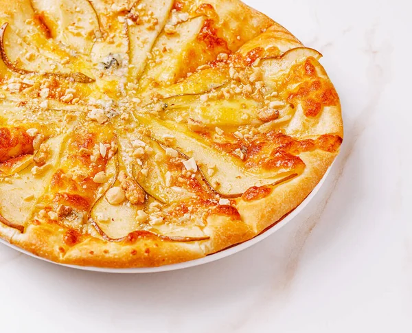 Lezzetli bir pizza, altın kabuklu taze armut dilimleri ve çıtır ceviz içerir. Peynir mükemmel bir şekilde eriyor ve tek başına yemek yemek için ideal bir davet oluşturuyor..