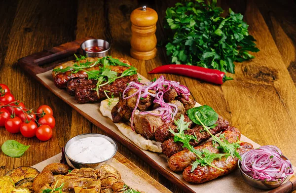 Ahşap bir tabakta çeşitli ızgara etler, soslar, taze otlar ve sebzelerle birlikte. Ziyafette lezzetli dokular, renkler ve baştan çıkarıcı kokular ön plana çıkıyor..