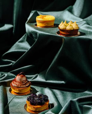 Yeşil kumaş sergilerinde sergilenen canlı tatlıların bir seçimi karmaşık tasarımlar ve dokular. Her tatlı eşsiz tatlar ve malzemeler içeriyor. Aşçılık sanatını ön plana çıkarıyor..