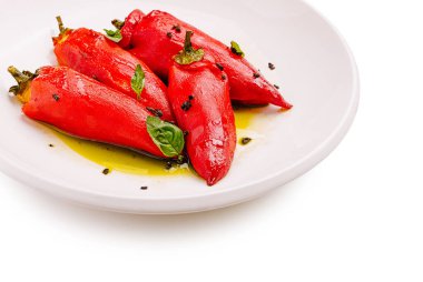 Taze kırmızı biberler beyaz bir tabağa düzgünce yerleştirilir, zeytinyağı serpiştirilir ve otlarla süslenir. Bu renkli sunum kesinlikle yemek sevenleri memnun edecek..
