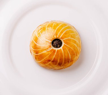 Bu nefis hamur işi, sarmal bir tasarımı ve ortasında beyaz bir tabakta güzelce sunulan zengin bir çikolatası olan altın-kahverengi bir dış görünüşü içeriyor..