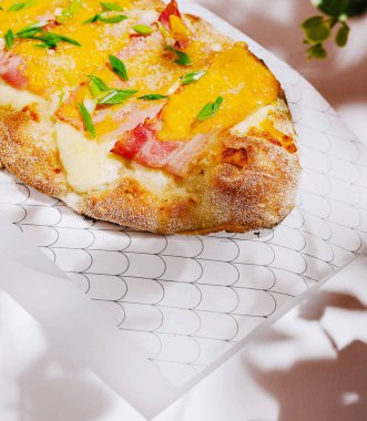 Sıcak bir ekmek, erimiş peynir ve dilimlenmiş jambonla kaplanır, yeşil soğanla süslenir, enfes bir ortamda dekoratif parşömen kağıdında servis edilir. Gündelik yemek için mükemmel..