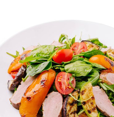 Renkli bir salatada taze ıspanak, ızgara sebze ve sulu ördek göğsü bulunur. Parlak kiraz domatesleri sağlıklı bir yemek için mükemmel olan bu lezzetli yemeğe canlı bir dokunuş ekler..