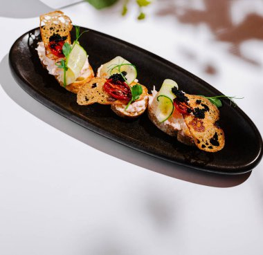 Özenle hazırlanmış bir deniz ürünleri yemeği zarif süslemeler ve eşsiz malzemeler içerir. Pürüzsüz siyah bir tabakta sunuluyor. Güzel bir lokantada mutfak işçiliği sergileniyor..