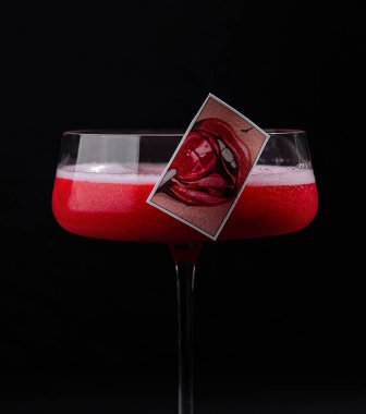 Canlı kırmızı bir katman ve dekoratif süsleme içeren sofistike bir kokteyl çarpıcı bir görüntü oluşturur.