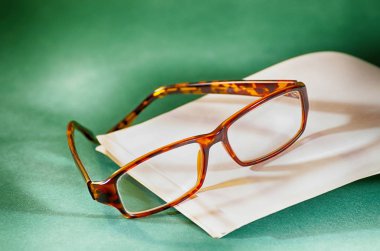Gözlük ve bir masanın üzerinde yatan bir kitap ile yeşil kumaş kaplı.