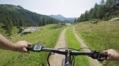 E-bike downhill yakın göl üzerinde Pov kişini. Mtb eylem bisikletçi iz yolu dağlar yakınındaki keşfetmek. Elektrikli bisiklet için etkin olan kişileri spor seyahat tatil Avrupa İtalya Alpleri'nde summer.4k video açık havada