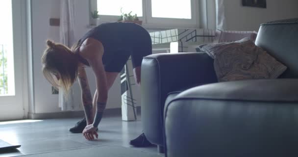 Young tattooed woman warming up doing stretching before fitness sport workout at home.Living room domestic training. 4k slow motion video — Stock Video