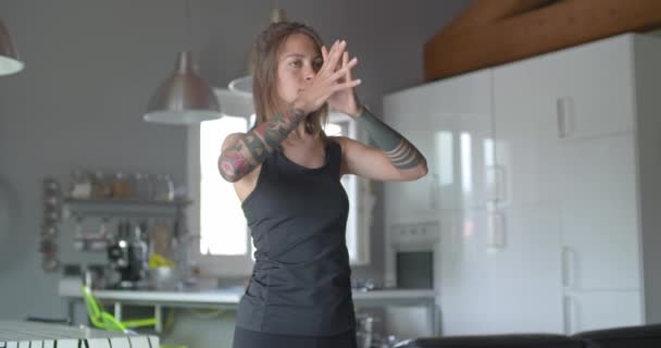 Ung tatuerad kvinna uppvärmning gör stretching innan fitness sport träning hemma. Vardagsrum med inhemska utbildning. 4 k slowmotion video — Stockvideo