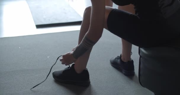 Tatuerade Kvinna knyta sina skor innan fitness sport träning hemma. Ben och skor detalj. . Vardagsrum med inhemska utbildning. 4 k slowmotion video — Stockvideo