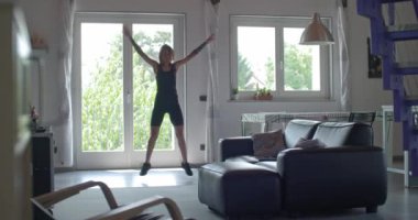 dövmeli kadın atlama yapıyor egzersiz ev fitness spor egzersiz sırasında vale. Oturma odası aile içi eğitim. 4 k ağır çekim video