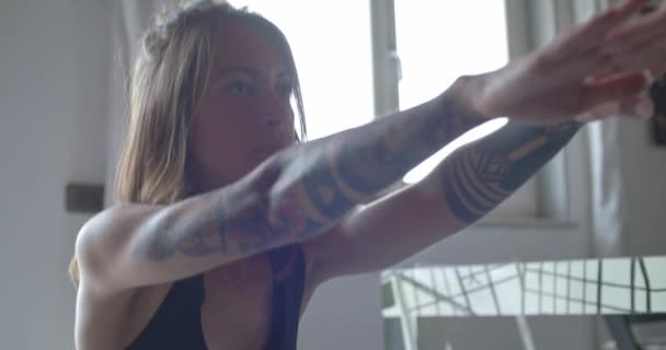 Ung tatuerade kvinna gör knäböj övning under hem fitness sport workout.detail på ansikte. Vardagsrum med inhemska utbildning. 4 k slowmotion video — Stockvideo