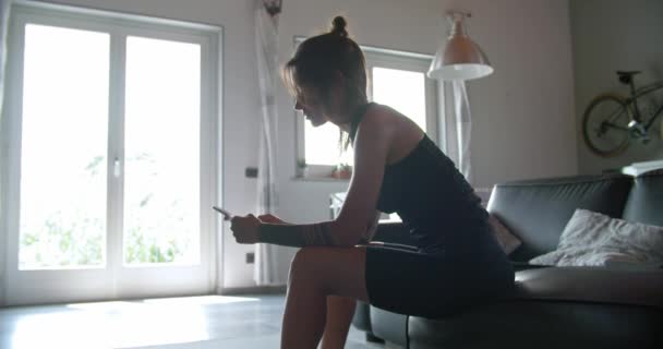 Νεαρή γυναίκα τατουάζ χρησιμοποιώντας smartphone για παρακολούθηση κατά τη διάρκεια της προπόνηση άθλημα της γυμναστικής στο σπίτι. Καθιστικό εσωτερικού κατάρτισης. 4 k βίντεο αργής κίνησης — Αρχείο Βίντεο