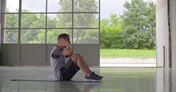 Молодой человек, выполняющий упражнения сидя во время занятий фитнесом. — стоковое видео