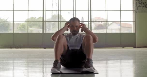 Молодий дорослий чоловік робить сидячі вправи під час тренувань з фітнесу. Перегляд фронту .Grunge промислове міське тренування.4k повільне відео руху — стокове відео