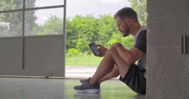 App fitness spor egzersiz sırasında izleme smartphone kullanan genç yetişkin adam. Grunge endüstriyel kentsel training.4k ağır çekim video — Stok video