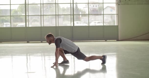 Hombre adulto joven que calienta el estiramiento durante el entrenamiento deportivo de la aptitud. Vista frontal. Grunge entrenamiento urbano industrial. 4k video en cámara lenta — Vídeo de stock