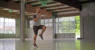 Genç yetişkin adam yüksek diz egzersiz fitness spor egzersiz sırasında atlama yapıyor. Grunge endüstriyel kentsel training.4k ağır çekim video